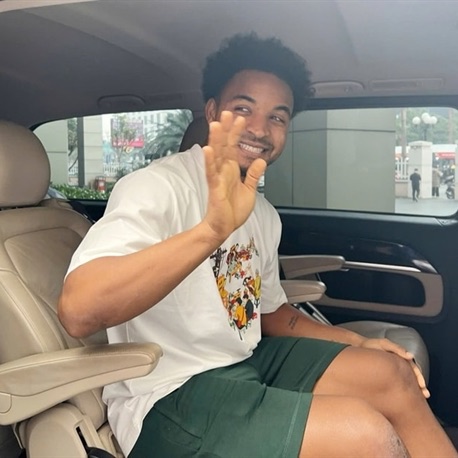 Nguyễn Xuân Son smiling and waving from the back seat of a car